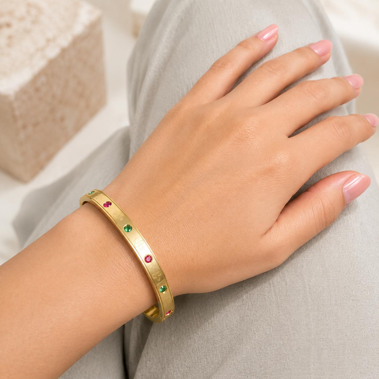Minimal gold bangle bracelet with green and pink gemstone accents