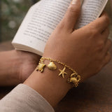 Gold ocean charm bracelet with turtle shell starfish crab charms on wrist